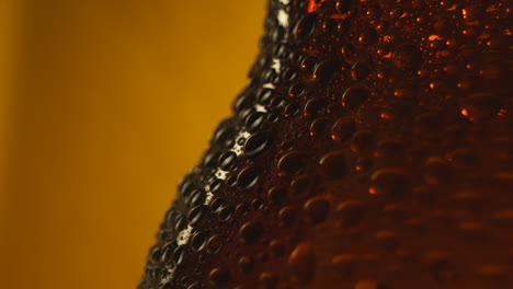 Macro-Shot-Of-Condensation-Droplets-On-Revolving-Bottle-Of-Cold-Beer-Or-Soft-Drinks-Against-Yellow-Background-3